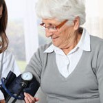 Closeup of nurse checking senior woman blood pressure