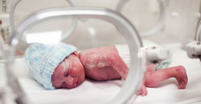 Newborn baby covered in vertix in incubator