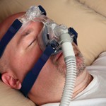 Man with sleep apnea using a CPAP machine in bed.