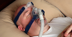 Man with sleep apnea using a CPAP machine in bed.