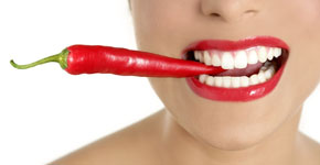 Beautiful woman teeth eating red pepper